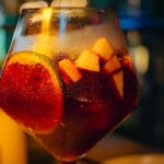 Vaso de sangría fría de verano con rodajas de fruta y hielo