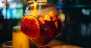 Vaso de sangría fría de verano con rodajas de fruta y hielo